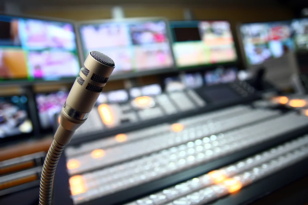 Broadcast control board with a microphone and bank of monitors
