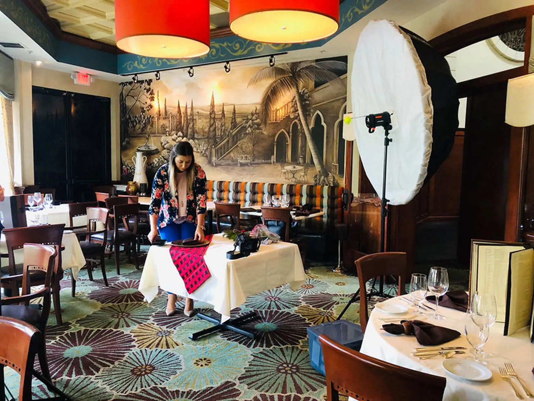 Photographer setting up a lit shoot of a dining table in a restaurant