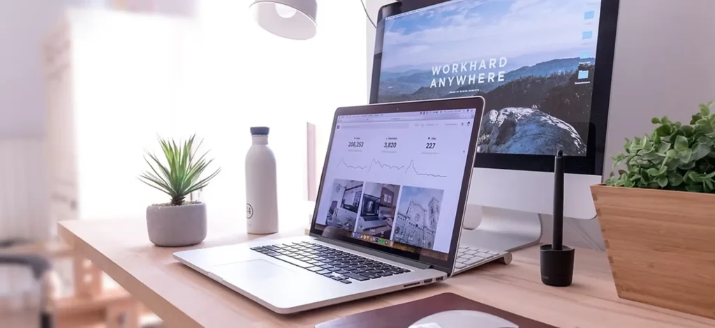 Laptop and desktop monitor on a tidy desk showing a website